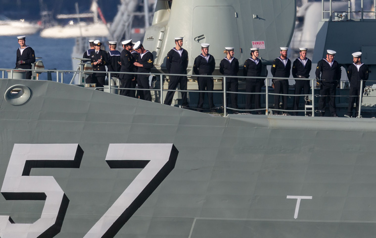 The Australian Navy standing on the deck of a ship with number 57 printed on the side.