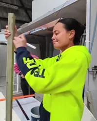 A woman marking a piece of timber in high vis 