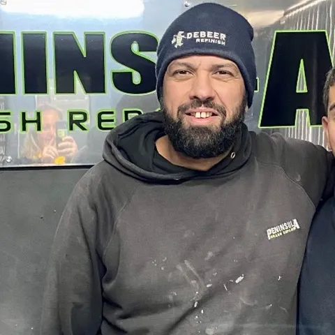 young man apprentice Employers How apprentices and trainees can grow your business Ben apprentice panel beater standing with work colleague indoors clothing human beard human face indoor jacket jeans man person smile wall