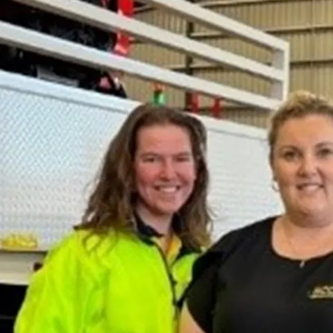 mechanic workshop indoors smiling high vis Employers How apprentices and trainees can grow your business Melissa two women standing in front of a flat bed with crane auto part automobile repair shop automotive tire clothing footwear indoor jeans land vehicle man person service standing tire transport truck vehicle wheel