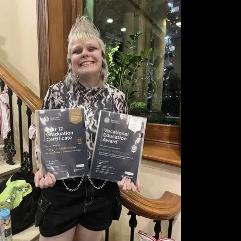 Person with a wide smile holding certificates