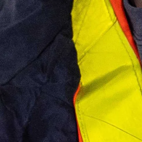 Young male in safety gear holding a tool on a construction site.