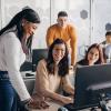 Office workers smiling and sitting at computer