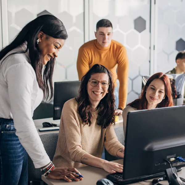 Office workers smiling and sitting at computer