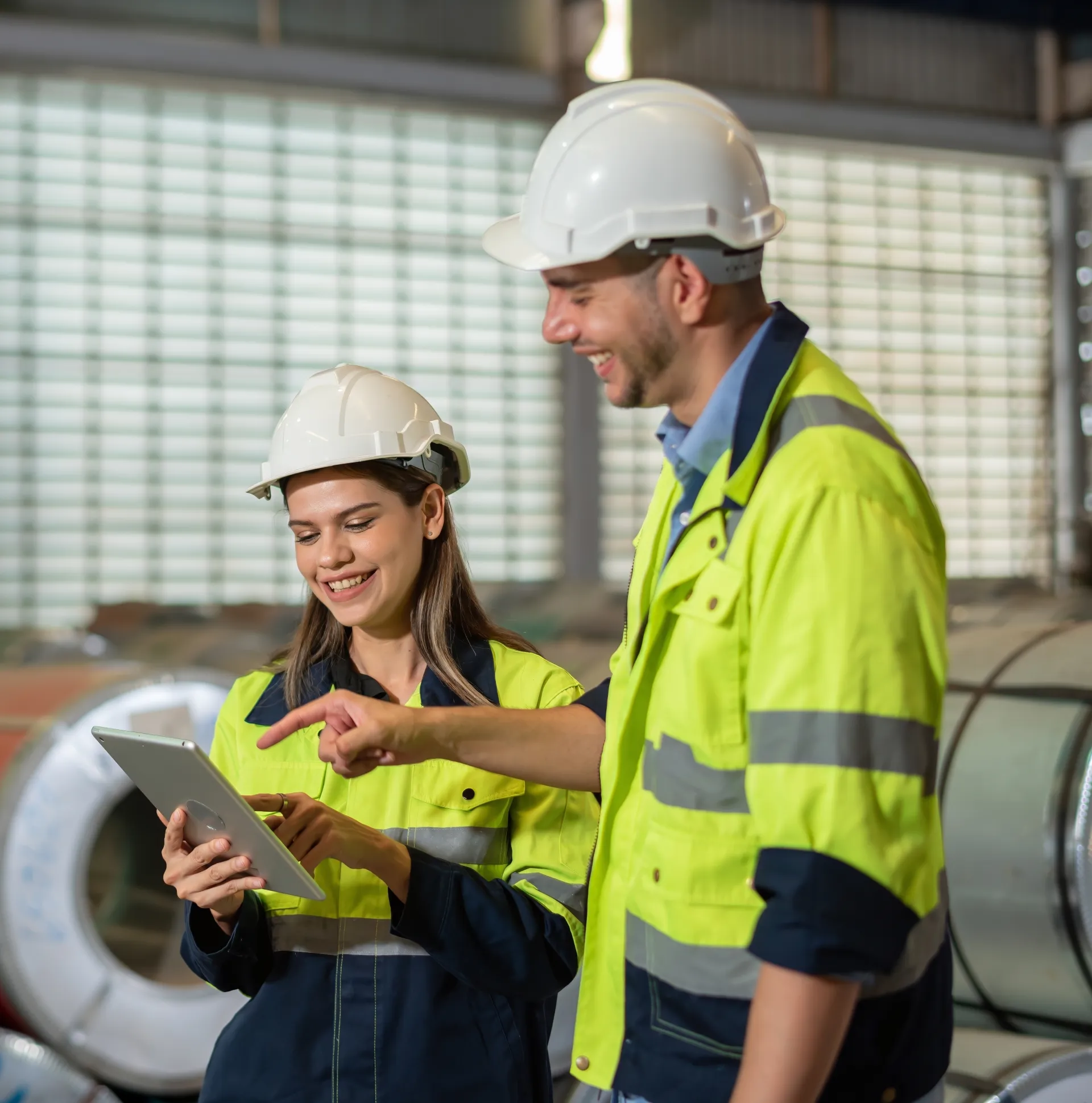 two people wearing high-visibility clothing holding device smiling