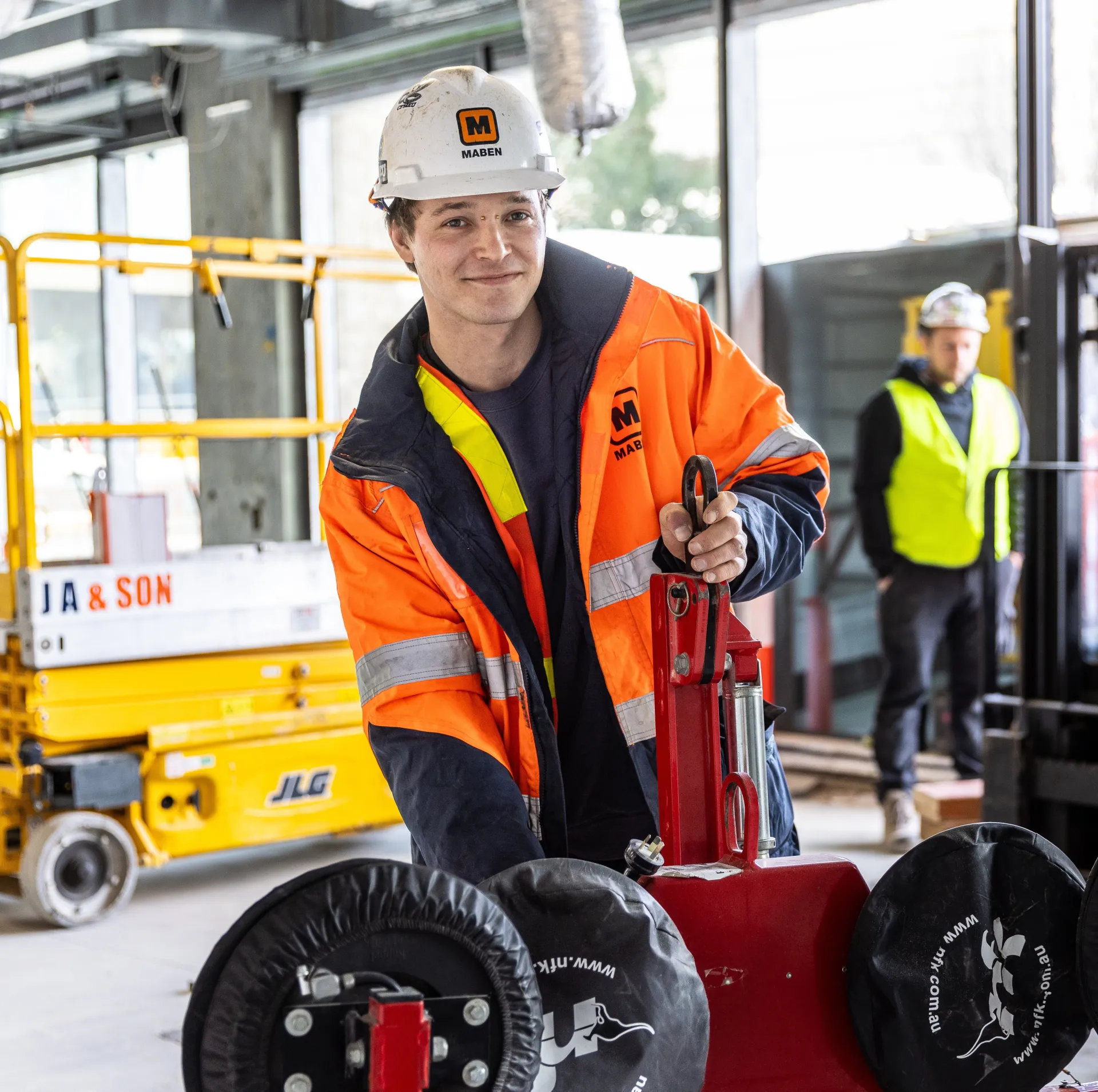 Young worker wearing hi vis and hard hat holding equipment