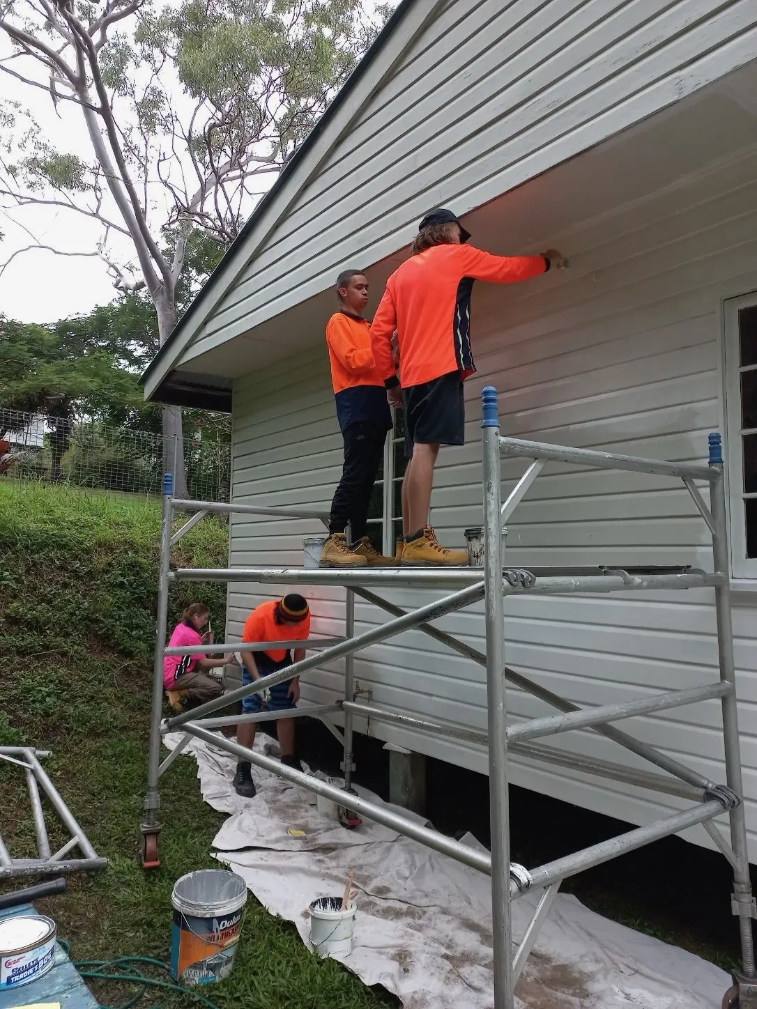 Two painters on scaffold painting house